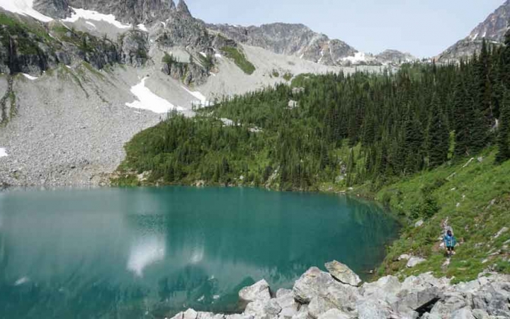 a blue alpine lake sits amount green trees and gray mountains in the pacific northwest